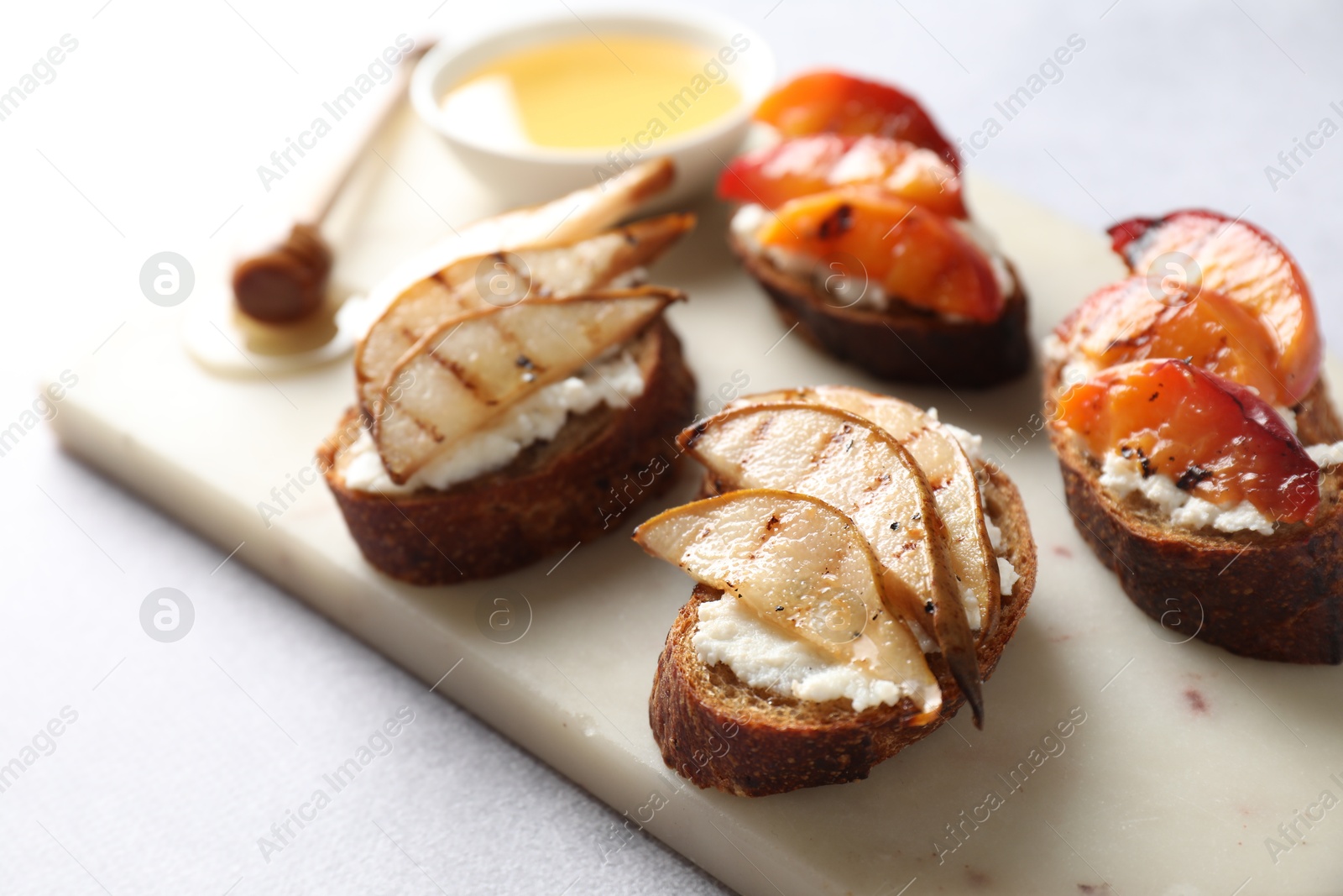 Photo of Delicious bruschettas with ricotta cheese and honey on light grey table, closeup