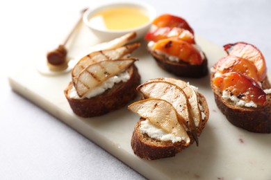 Photo of Delicious bruschettas with ricotta cheese and honey on light grey table, closeup