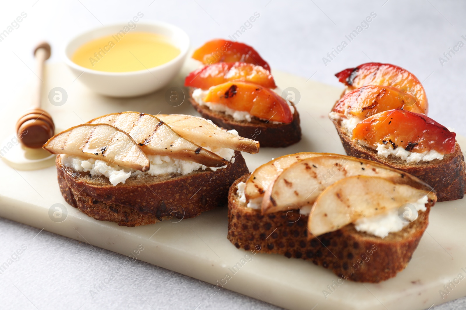 Photo of Delicious bruschettas with ricotta cheese and honey on light grey table, closeup