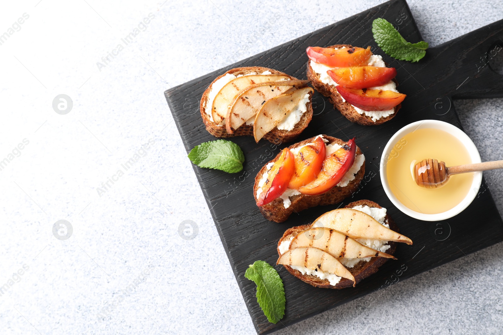 Photo of Delicious bruschettas with ricotta cheese and honey on light grey table, top view. Space for text