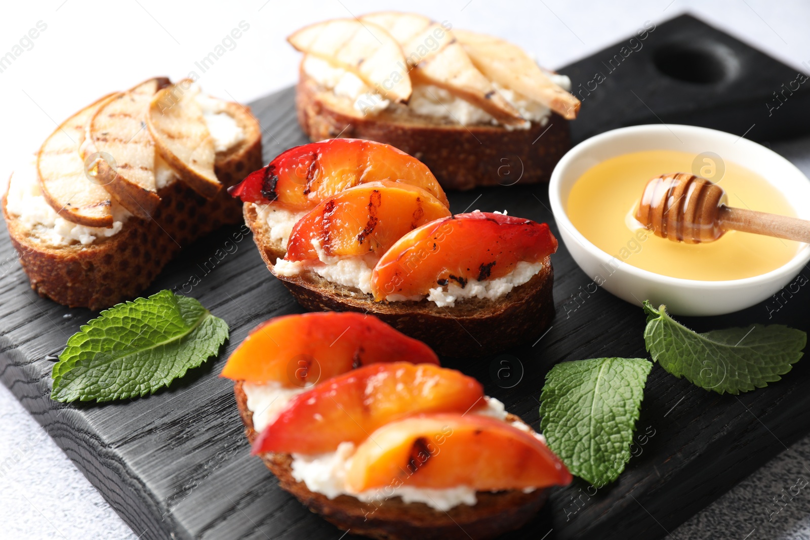 Photo of Delicious bruschettas with ricotta cheese and honey on light grey table, closeup