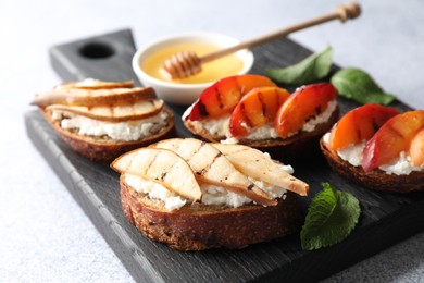 Delicious bruschettas with ricotta cheese and honey on light grey table, closeup