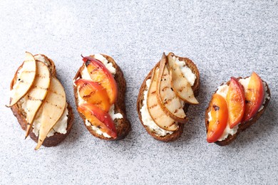 Delicious bruschettas with ricotta cheese on light grey table, top view