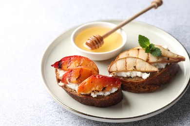 Delicious bruschettas with ricotta cheese and honey on light grey table, closeup