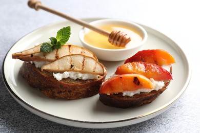 Delicious bruschettas with ricotta cheese and honey on light grey table, closeup