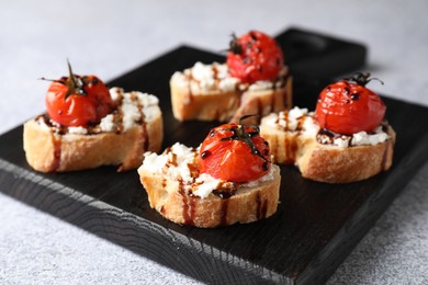 Bruschettas with ricotta cheese, tomatoes and balsamic sauce on grey table, closeup