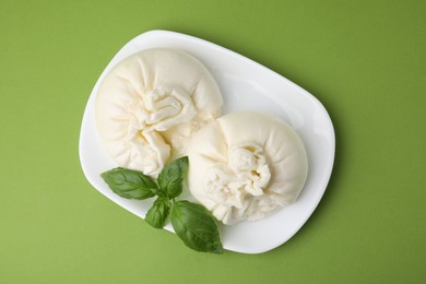 Delicious burrata cheese on green table, top view