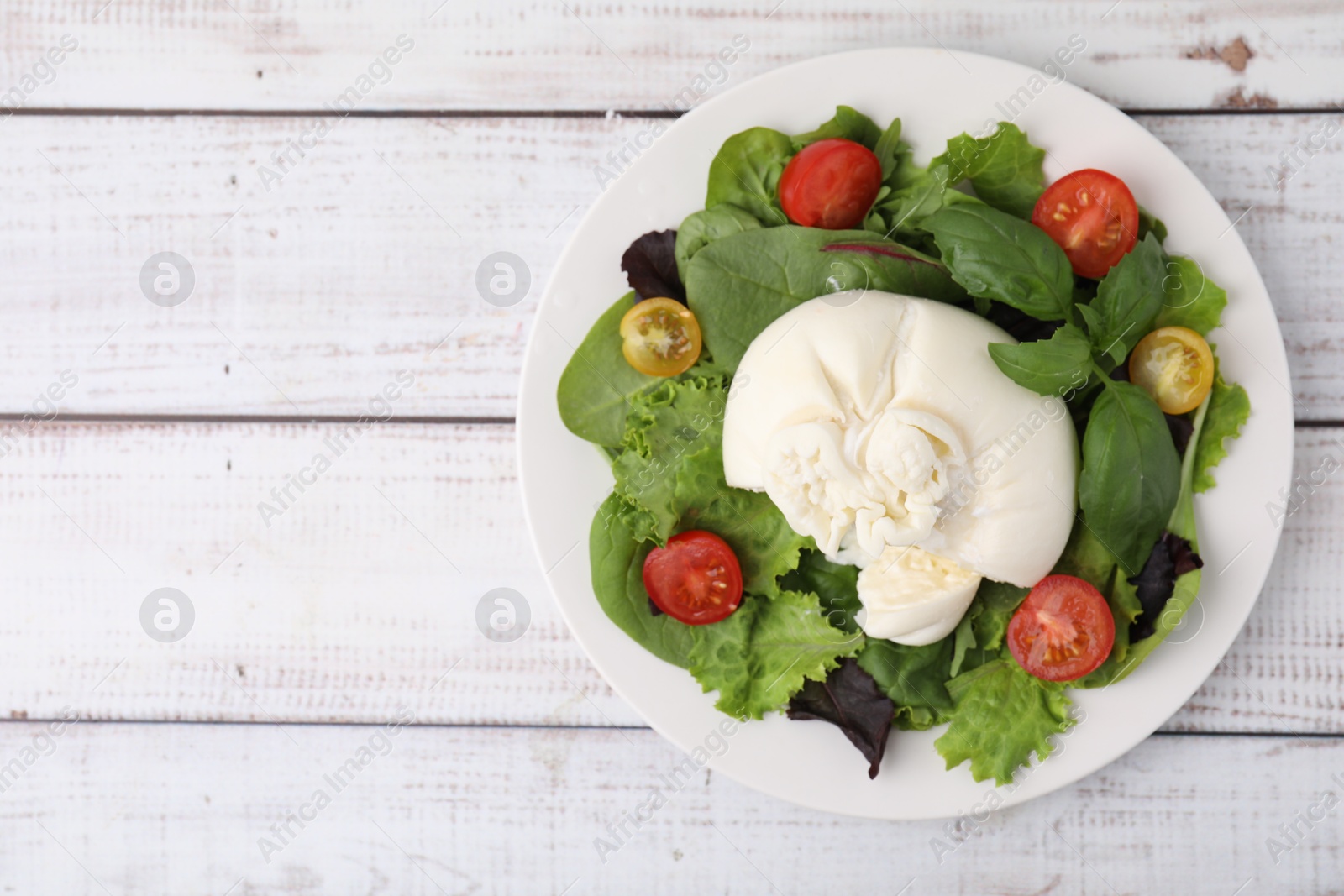 Photo of Delicious fresh burrata salad on white wooden table, top view. Space for text