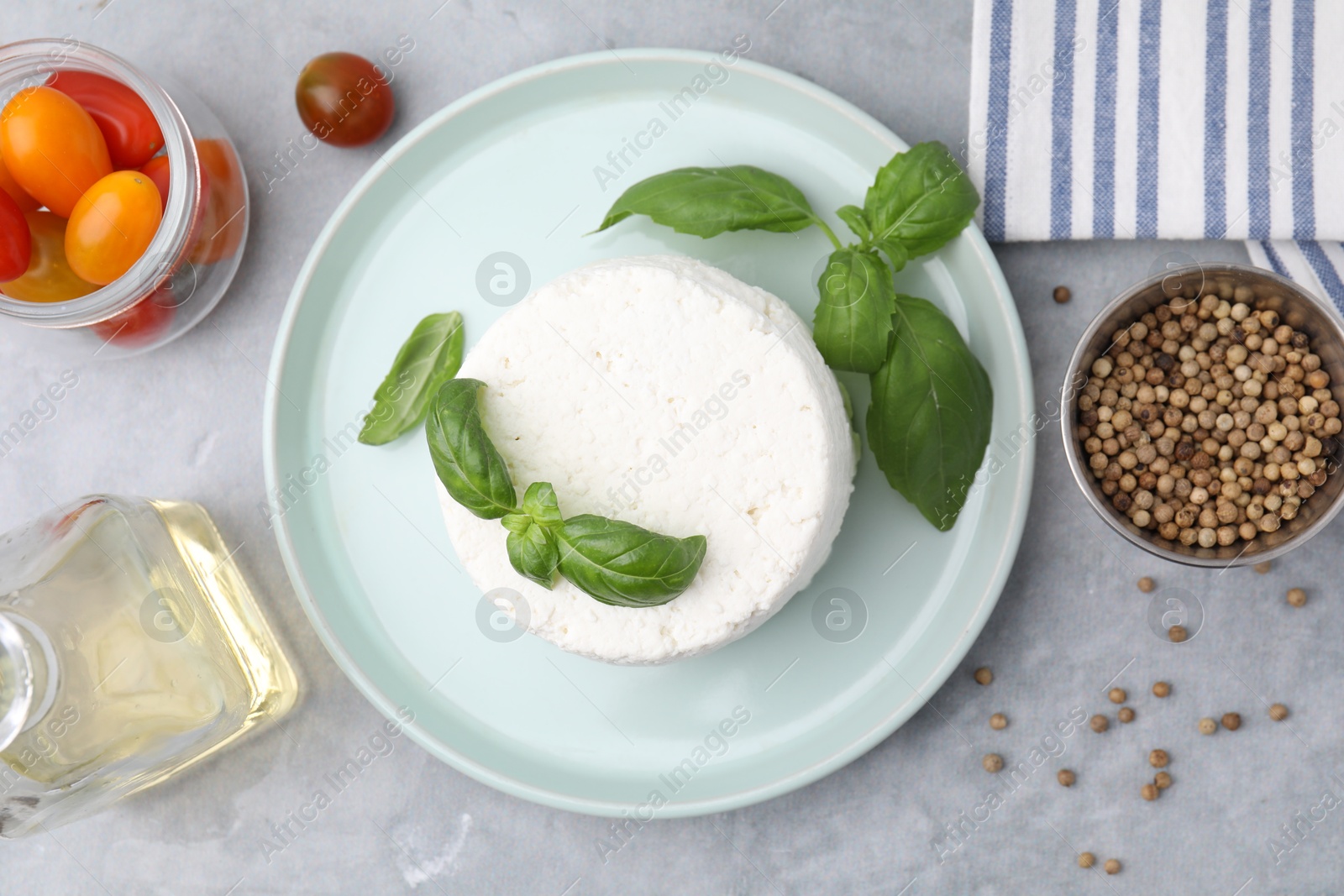 Photo of Fresh ricotta (cream cheese) and basil on gray table, flat lay