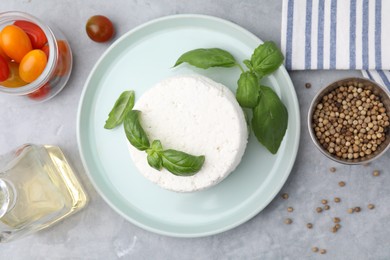 Photo of Fresh ricotta (cream cheese) and basil on gray table, flat lay