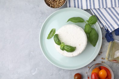 Photo of Fresh ricotta (cream cheese) and basil on gray table, flat lay. Space for text