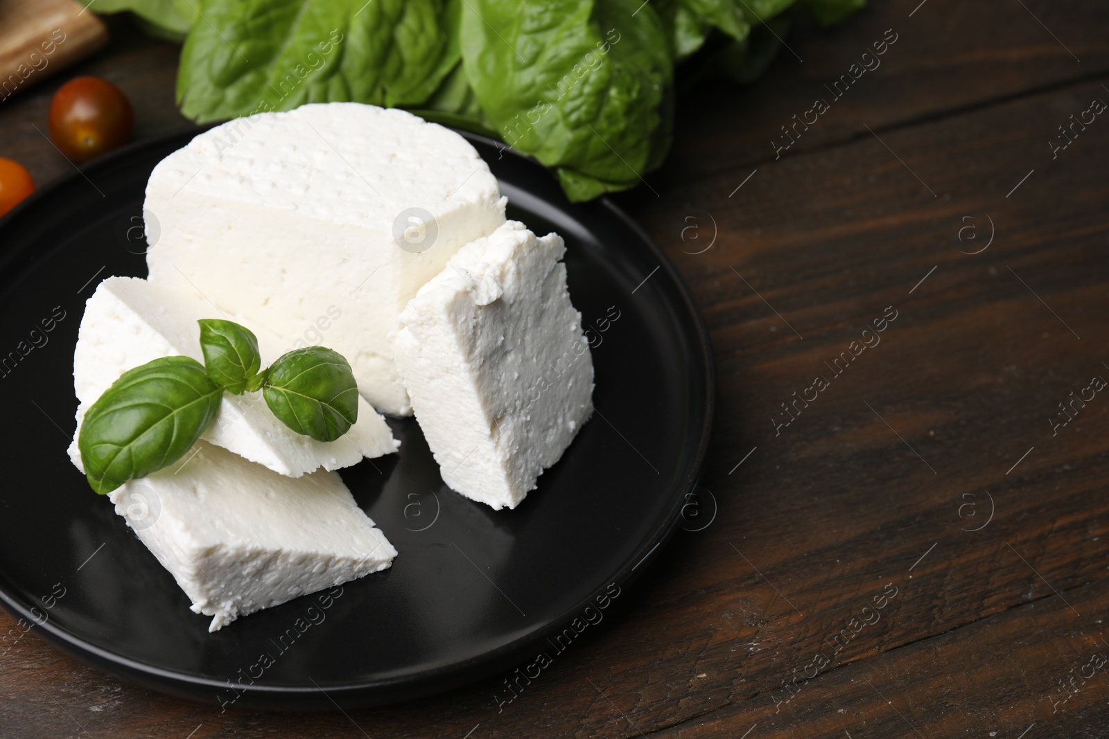 Photo of Fresh ricotta (cream cheese) and basil on wooden table, closeup. Space for text