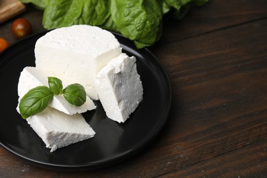 Photo of Fresh ricotta (cream cheese) and basil on wooden table, closeup. Space for text