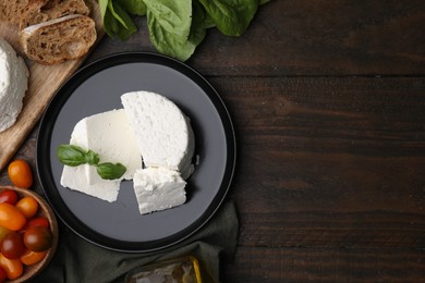 Fresh ricotta (cream cheese), basil and other products on wooden table, flat lay. Space for text