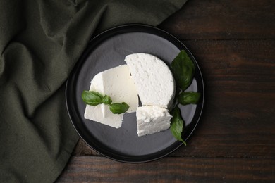 Fresh ricotta (cream cheese) and basil on wooden table, top view