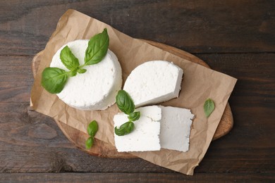 Photo of Fresh ricotta (cream cheese) and basil on wooden table, top view