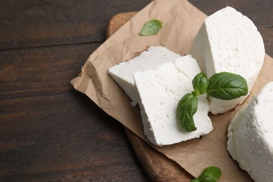 Fresh ricotta (cream cheese) and basil on wooden table, top view. Space for text