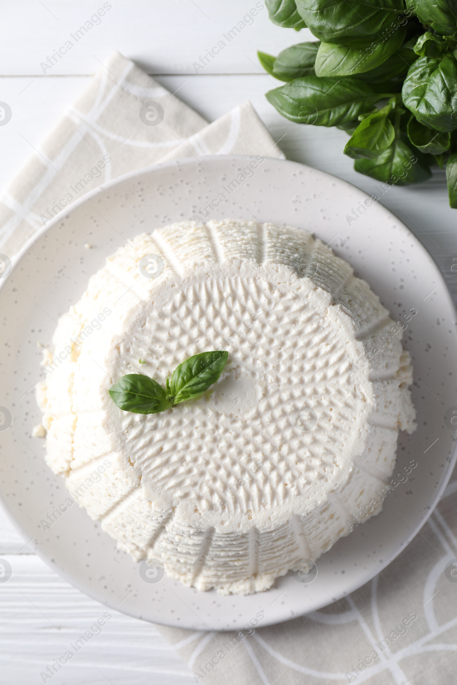 Photo of Tasty ricotta (cream cheese) and basil on white wooden table, flat lay