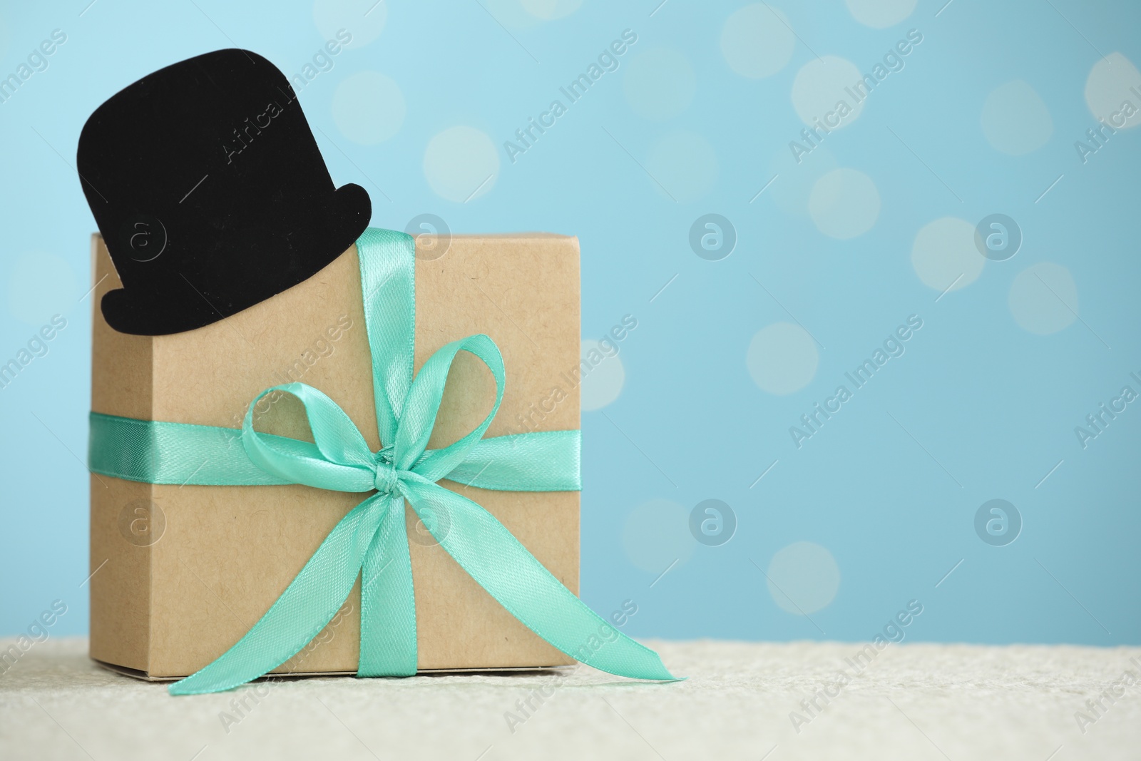 Photo of Happy Father's Day, gift box and paper hat on light table, space for text