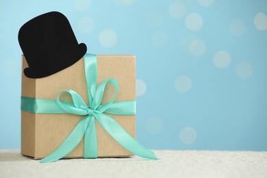 Happy Father's Day, gift box and paper hat on light table, space for text