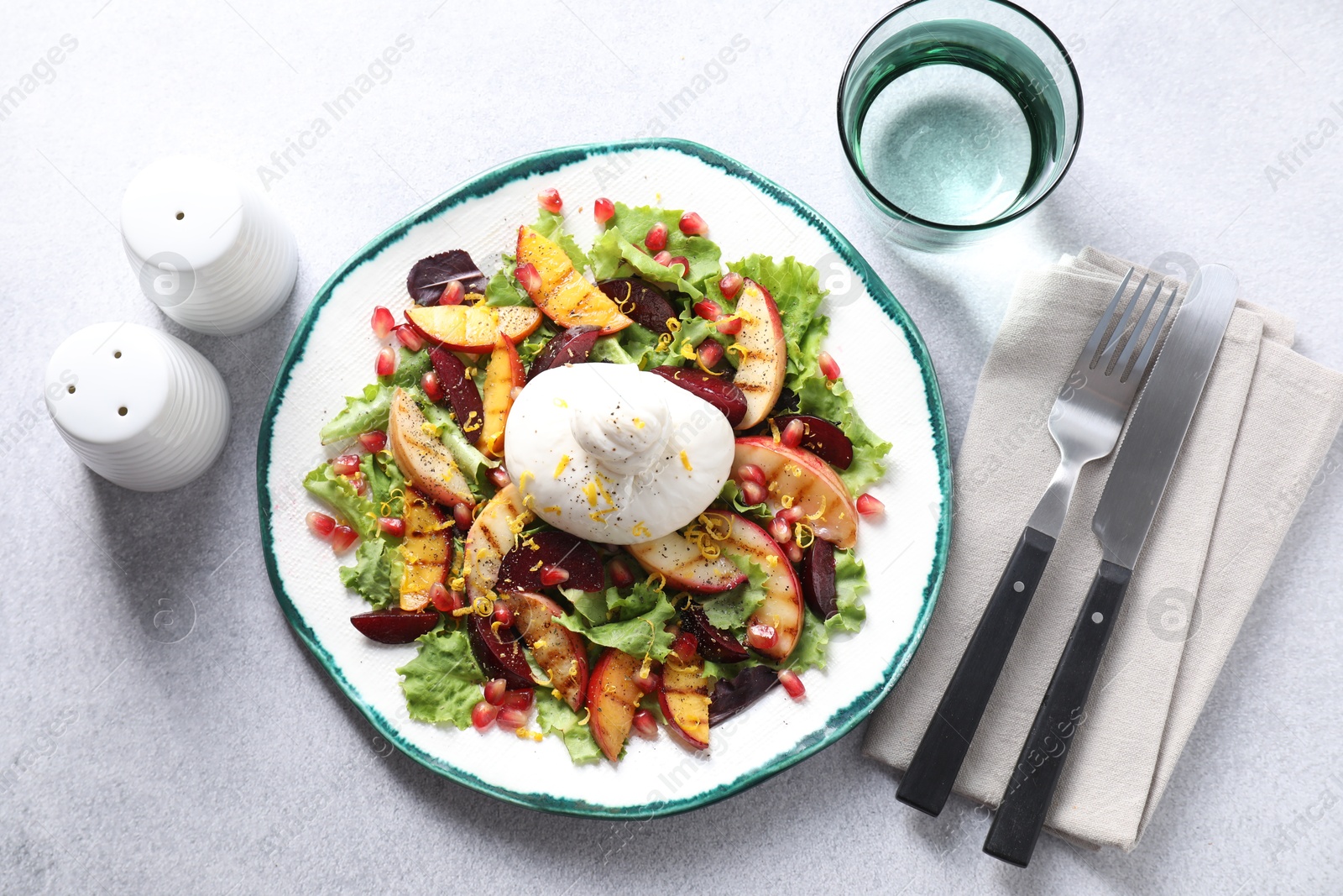 Photo of Plate with fresh burrata salad served on grey textured table, flat lay