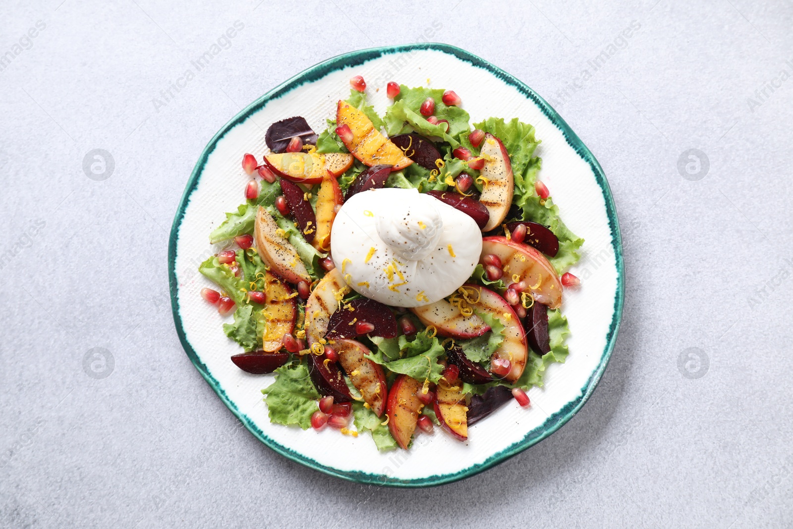 Photo of Plate with fresh burrata salad on grey textured table, top view