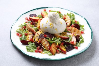 Plate with fresh burrata salad on grey table, closeup