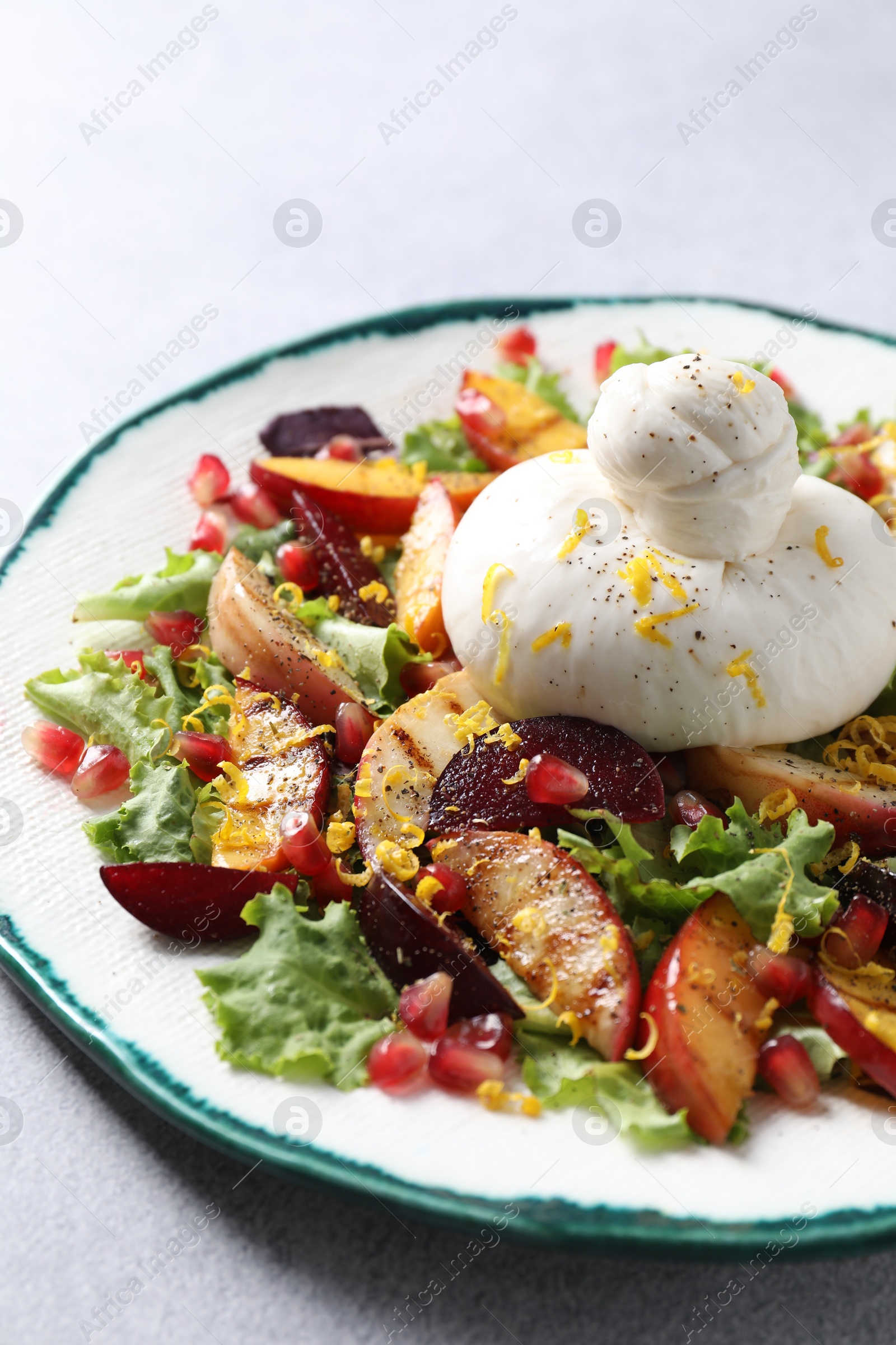 Photo of Plate with fresh burrata salad on grey table, closeup