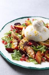 Photo of Plate with fresh burrata salad on grey table, closeup