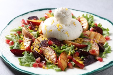 Plate with fresh burrata salad on grey table, closeup