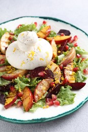 Plate with fresh burrata salad on grey table, closeup