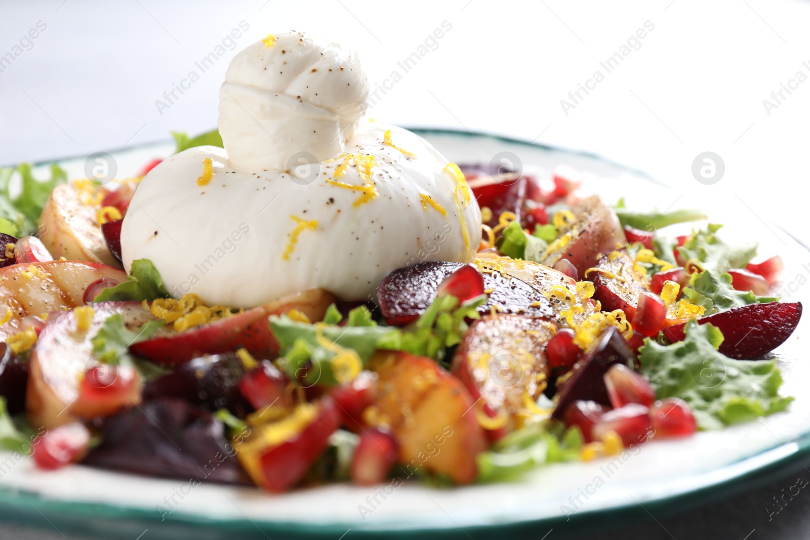 Photo of Plate with fresh burrata salad on table, closeup