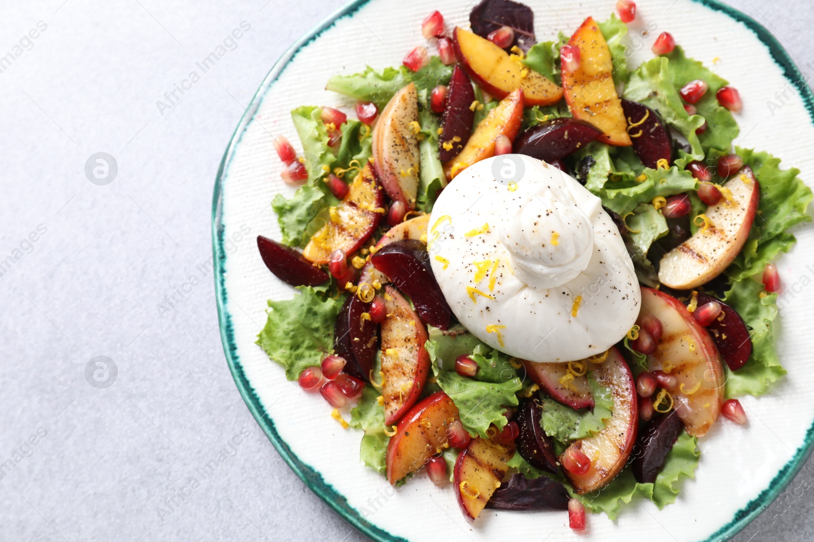 Photo of Plate with fresh burrata salad on grey textured table, top view