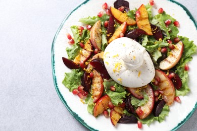 Plate with fresh burrata salad on grey textured table, top view