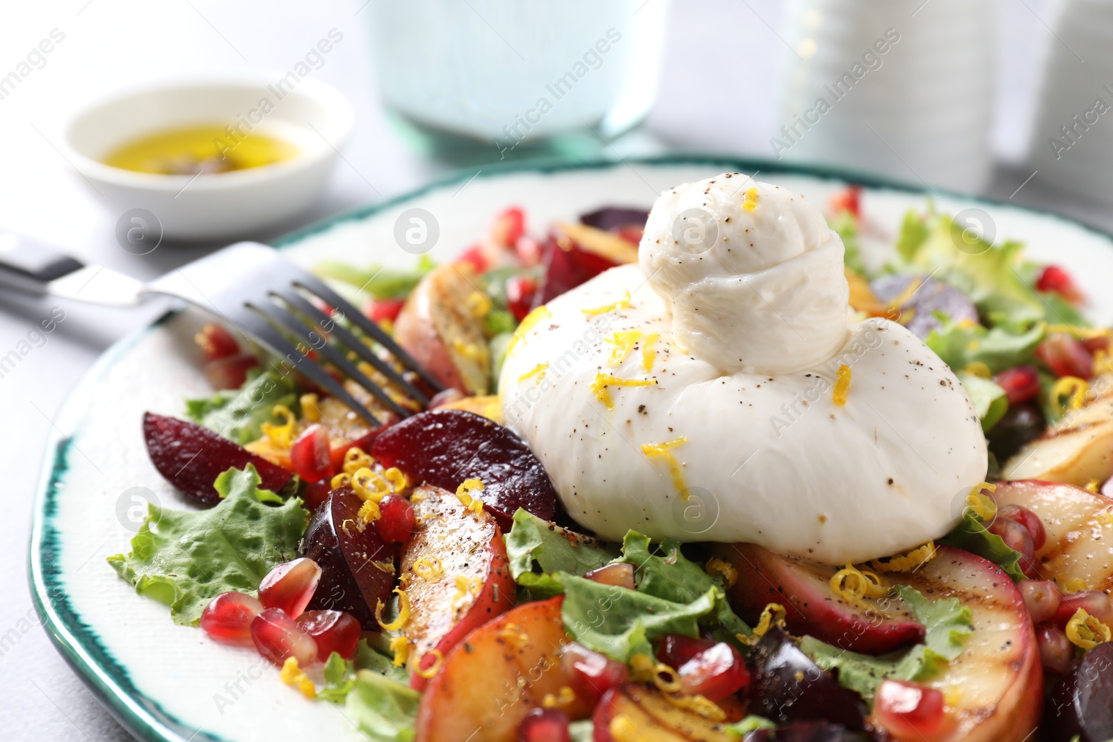 Photo of Plate with fresh burrata salad on table, closeup