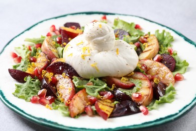 Photo of Plate with fresh burrata salad on grey table, closeup