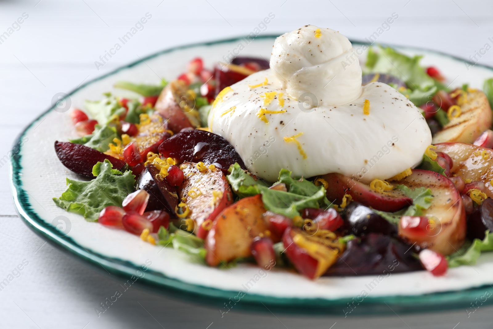 Photo of Plate with fresh burrata salad on white wooden table, closeup