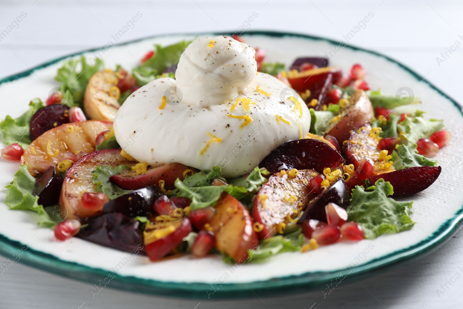 Photo of Plate with fresh burrata salad on white wooden table, closeup