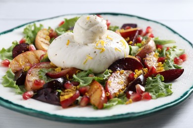 Plate with fresh burrata salad on white wooden table, closeup