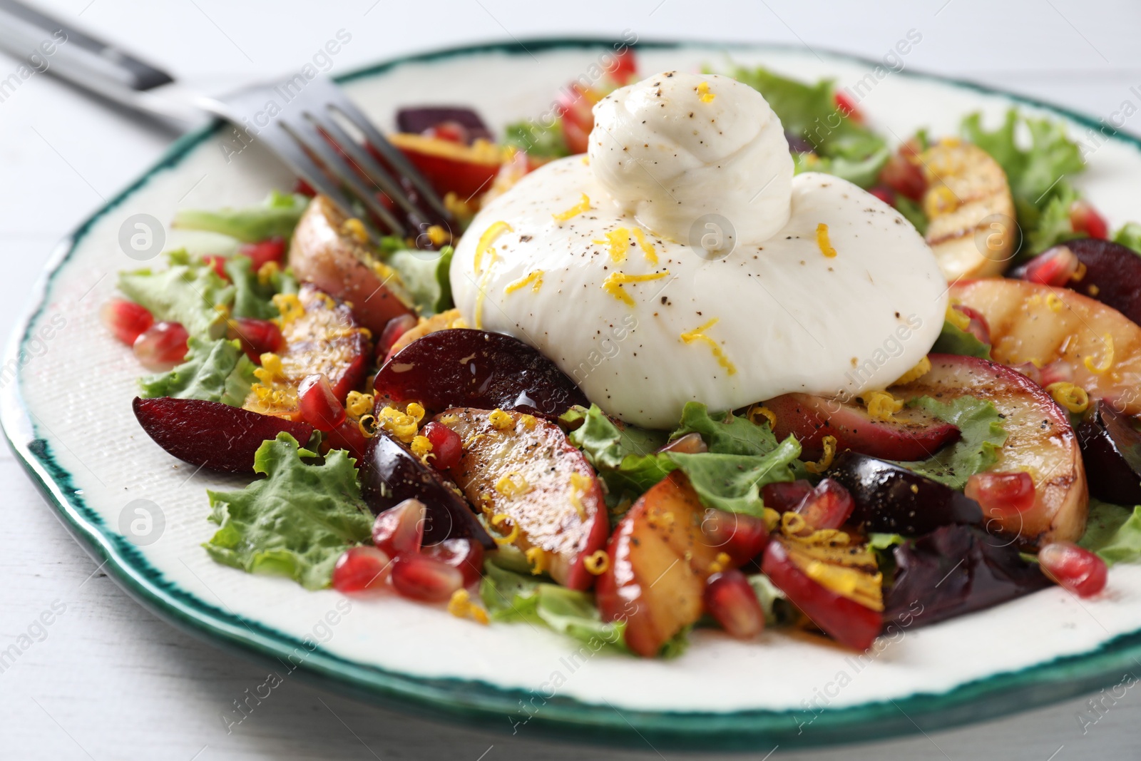 Photo of Plate with fresh burrata salad on white wooden table, closeup