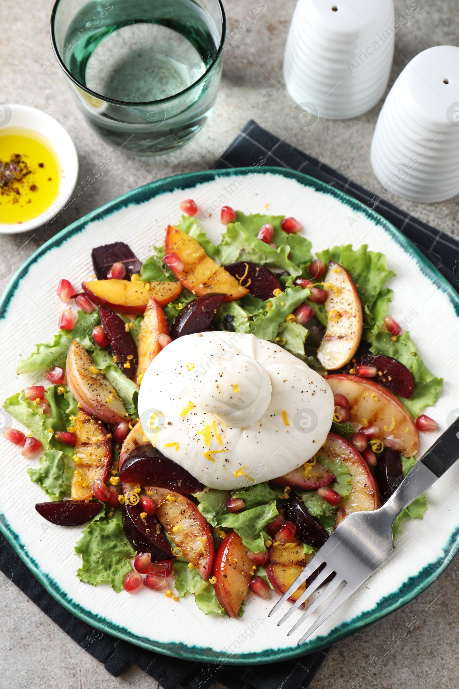 Photo of Plate with fresh burrata salad served on grey textured table, flat lay