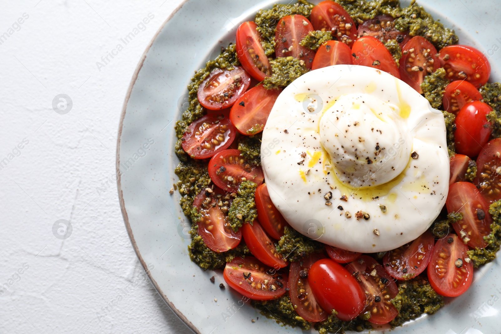 Photo of Fresh delicious burrata salad on white table, top view