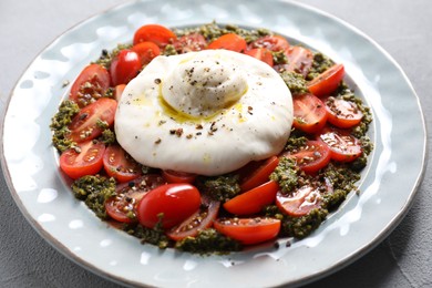 Fresh delicious burrata salad on light grey table, closeup