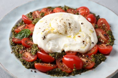 Fresh delicious burrata salad on table, closeup