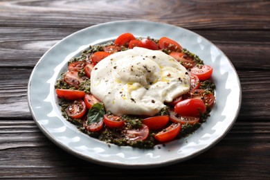 Fresh delicious burrata salad on wooden table, closeup