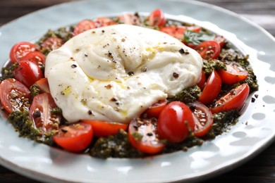 Fresh delicious burrata salad on table, closeup