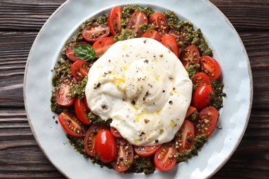 Fresh delicious burrata salad on wooden table, top view