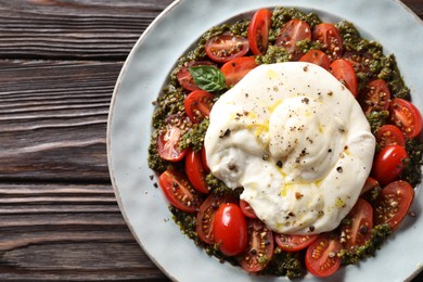 Photo of Fresh delicious burrata salad on wooden table, top view