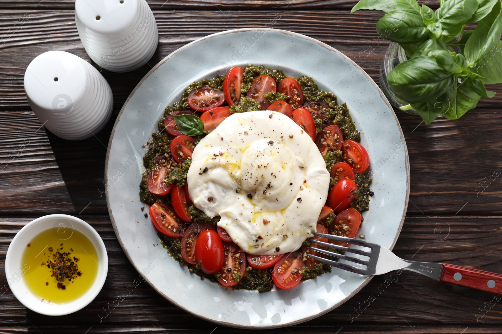 Photo of Fresh delicious burrata salad served on wooden table, top view