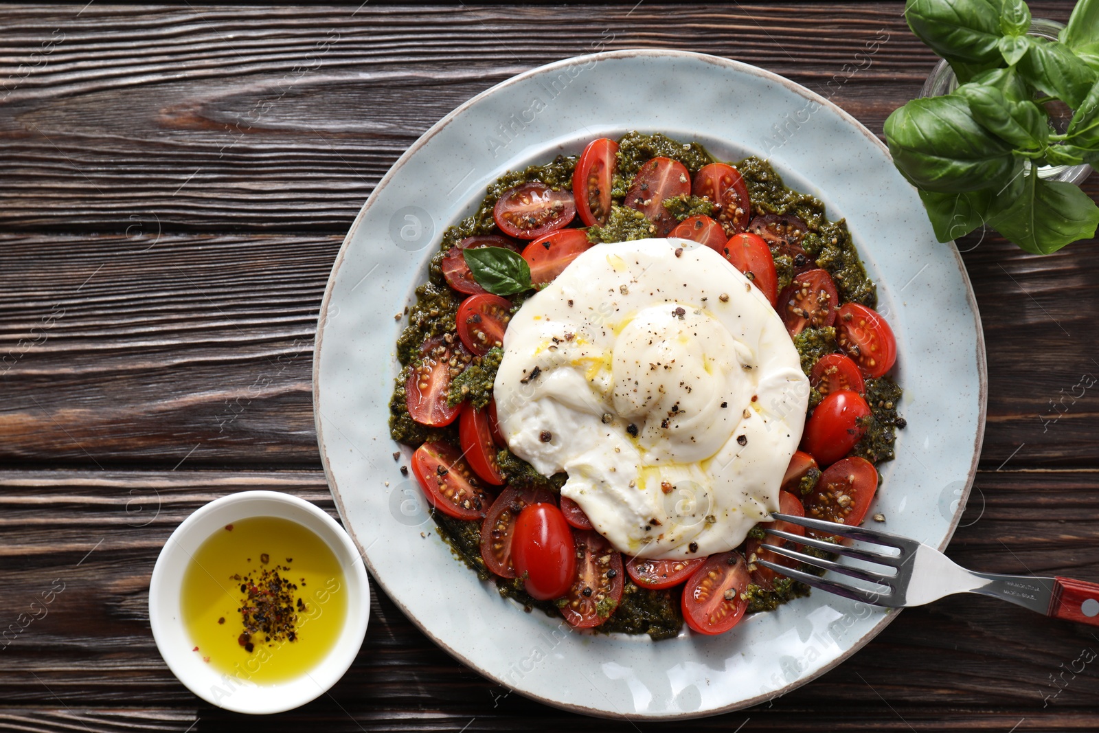 Photo of Fresh delicious burrata salad served on wooden table, top view